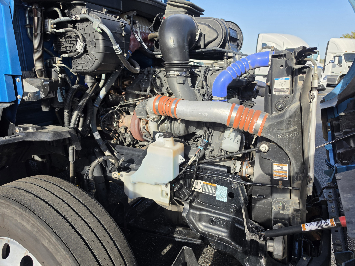 Kenworth T680 engine bay showing coolant reservoir, intercooler, hoses, and turbo components.