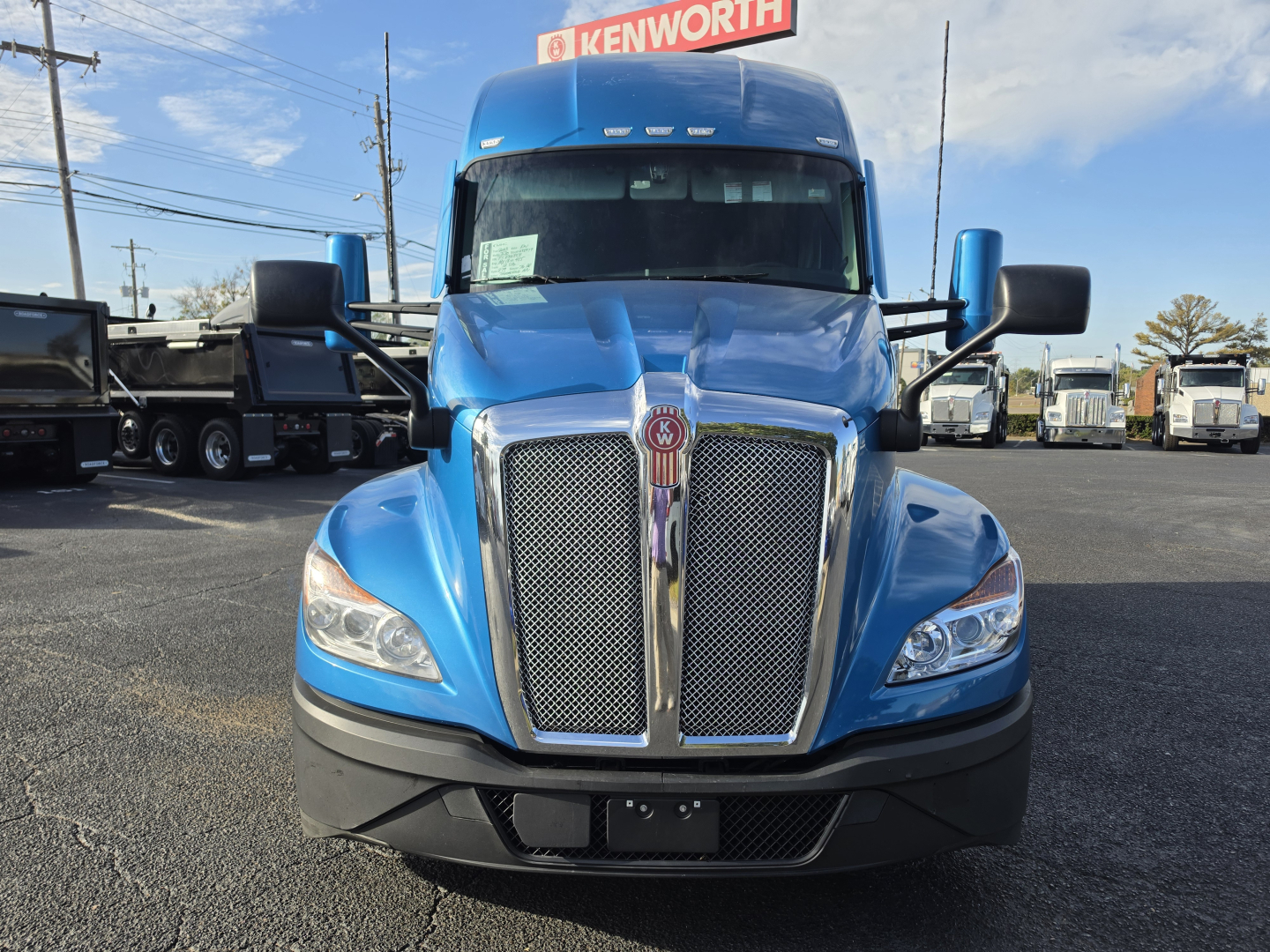 Kenworth T680 tractor front view showing chrome grille, blue cab, large bumper, and side mirrors.