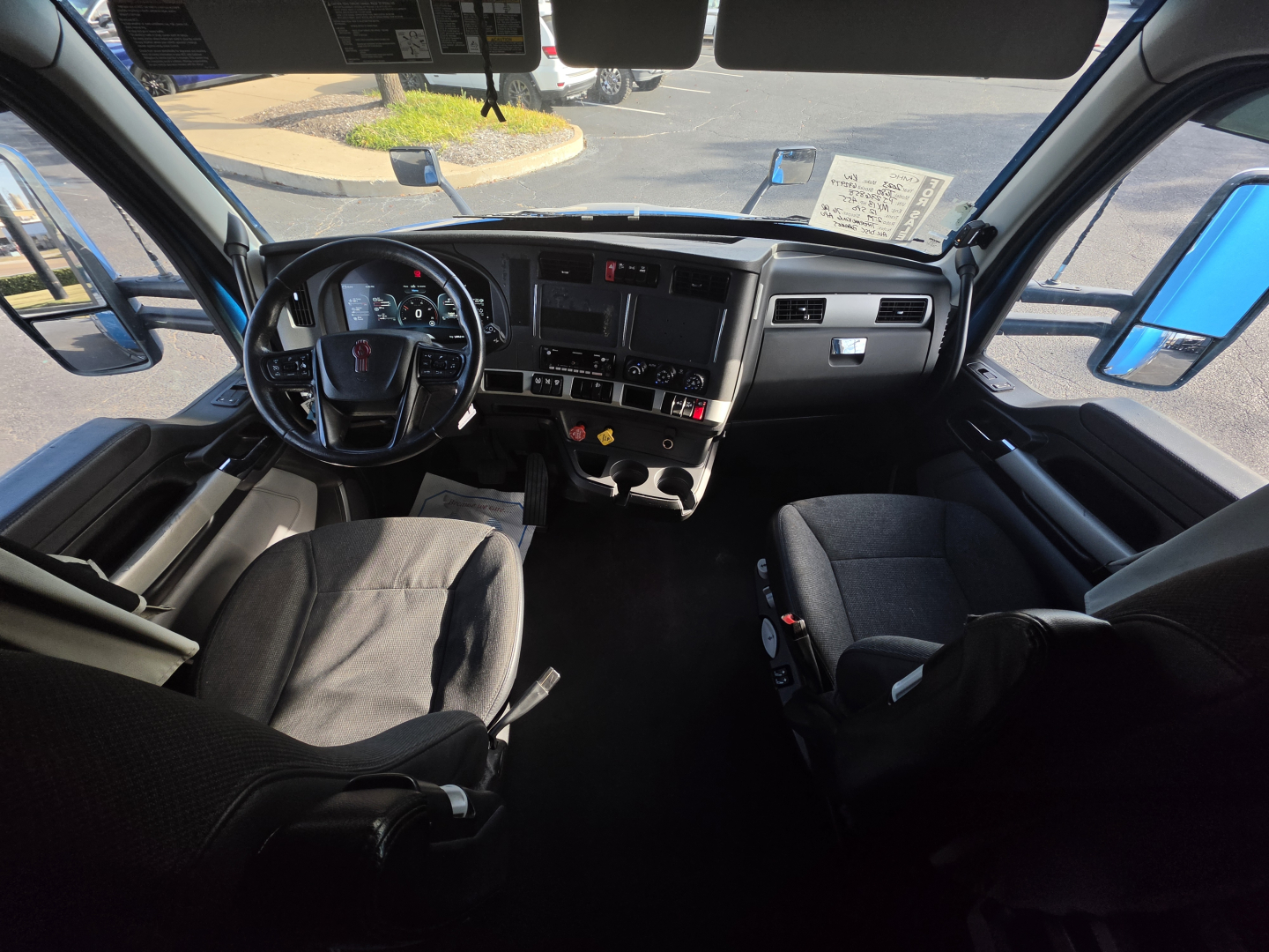 Kenworth T680 truck interior showing steering wheel, dashboard, and front seats from driver’s perspective.