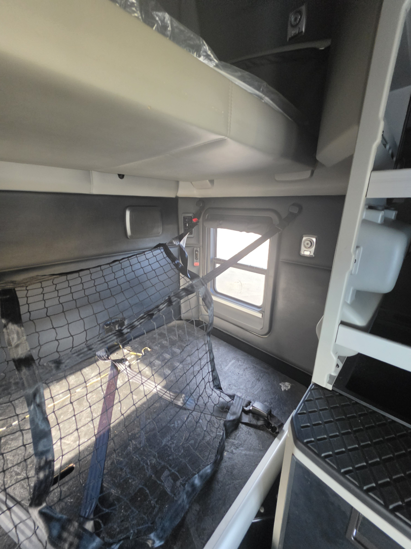 Kenworth T680 interior showing sleeper area and safety net, with side window and door frame visible.