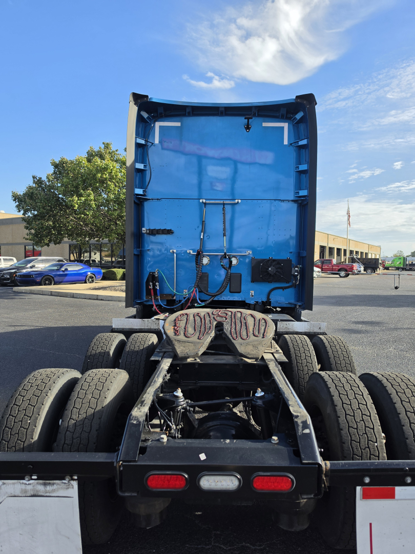 Kenworth T680 rear view showing fifth wheel and dual rear axles; blue sleeper cab interior visible from back.