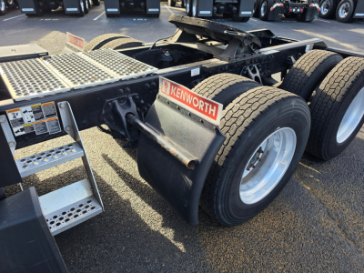 Kenworth T680 chassis showing dual rear axles and Kenworth badge on fender with metal steps and wheel tires in the foreground.