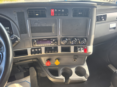 Kenworth T680 dashboard center console showing control switches, air vents, gauges, red hazard button, and two cup holders