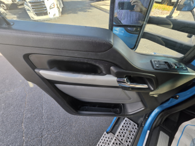 Kenworth T680 truck interior door panel with controls and chrome handle, blue exterior visible through window.