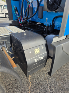 Kenworth T680 truck rear engine bay showing a black Box labeled Tripac Evolution with TB logo and cooling fan visible.