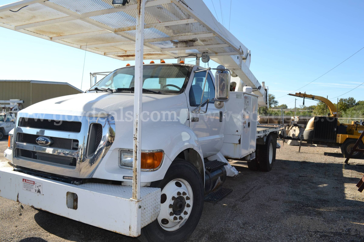 Ford F-750 bucket truck in-service showing front grille, cab, and ladder rack with hydraulic boom on the back.