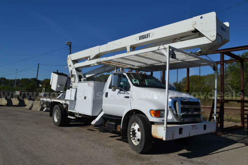 Versalift bucket truck on a white Ford F-750 utility chassis with boom raised.