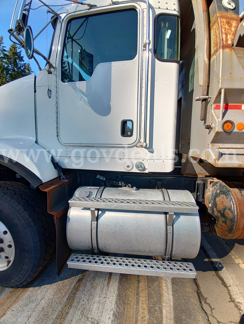 Kenworth T800B cab side with chrome door, steps, and fuel tanks; headlights and mirrors visible; part of dump bed on right.