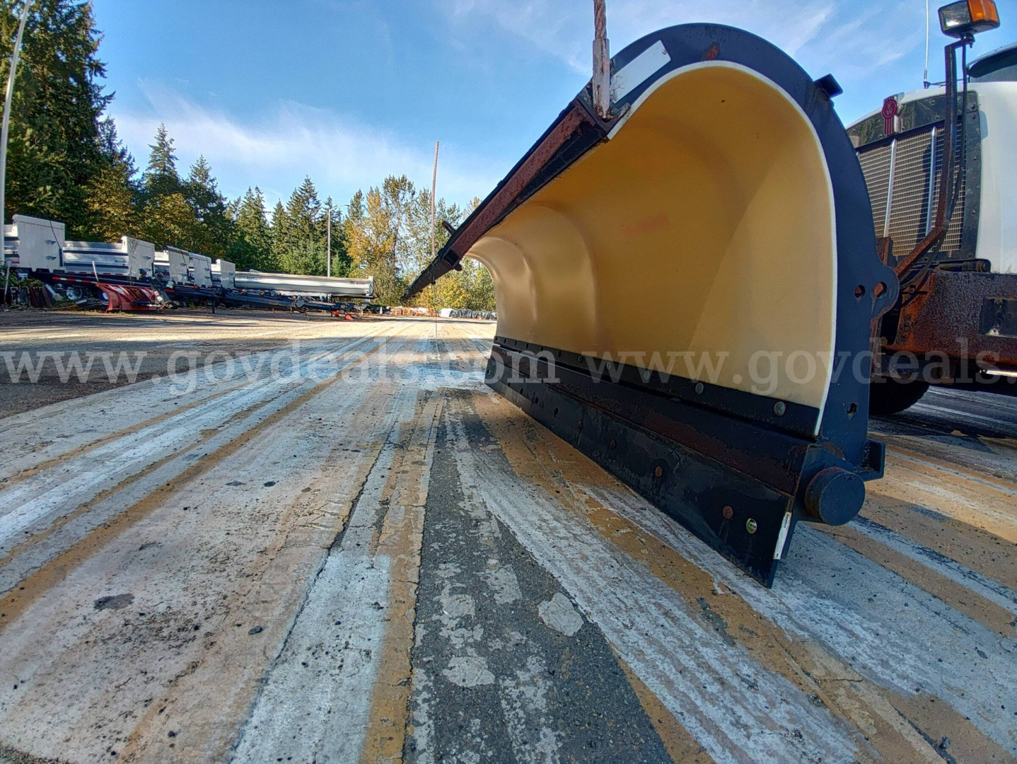 Kenworth T800B snowplow scoop blade attachment in a dump truck yard showing front cutting edge and yellow scoop interior