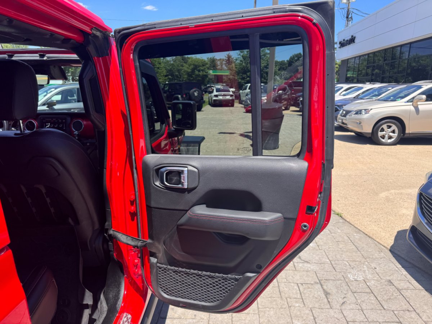 Jeep Gladiator suv interior door panel image showing open rear door with red exterior and black interior trim.