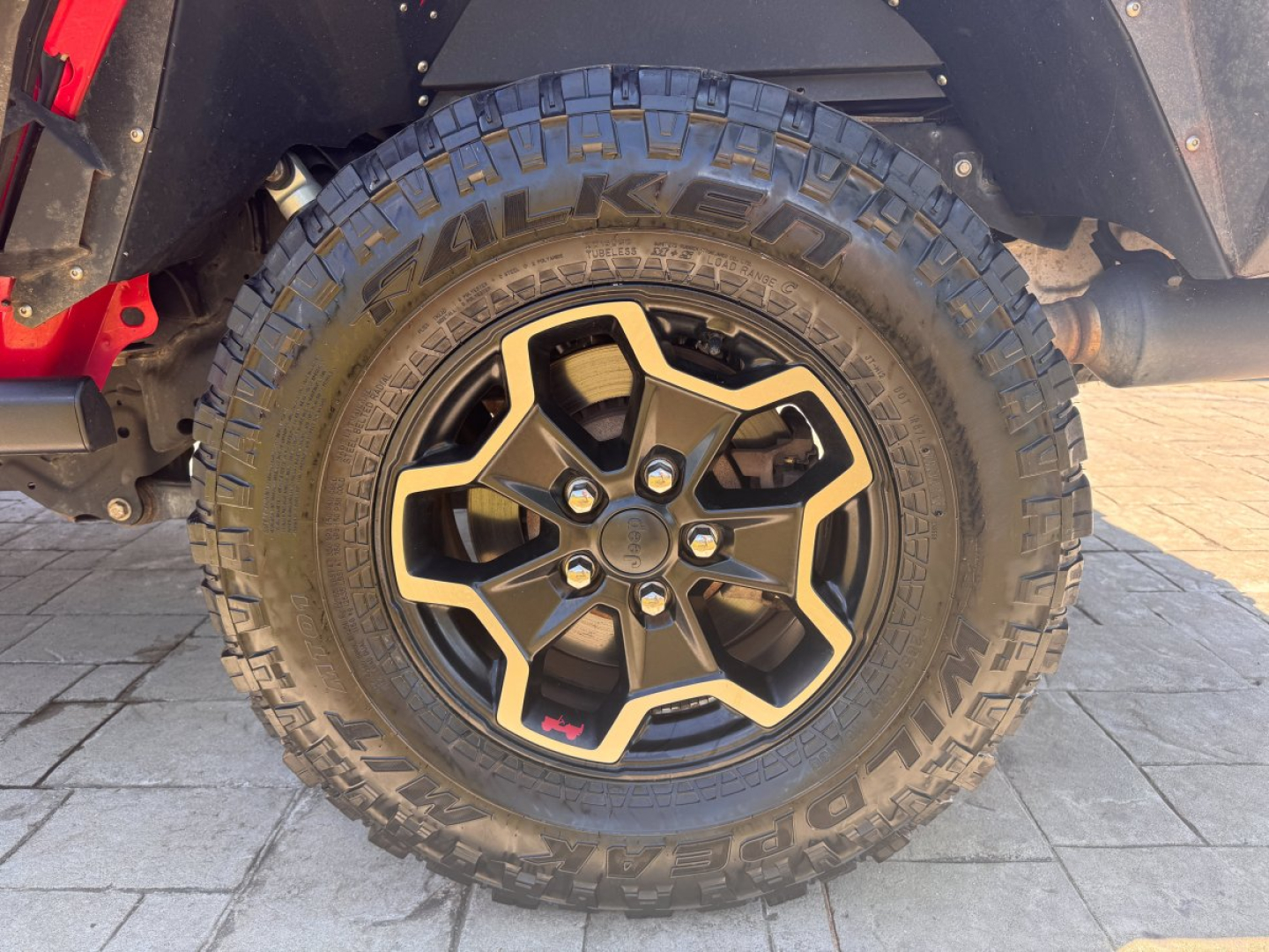 Close-up of front wheel and fender on a 2021 Jeep Gladiator showing rugged Falken tires and black alloy wheel with beige accents.