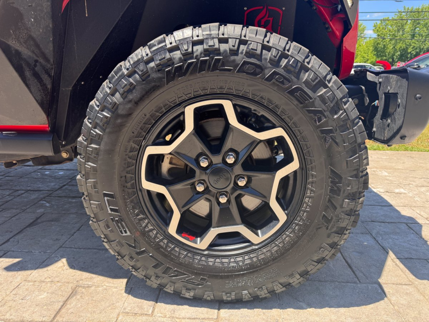 Jeep Gladiator front wheel and tire close-up showing rugged off-road tire and black alloy rim.