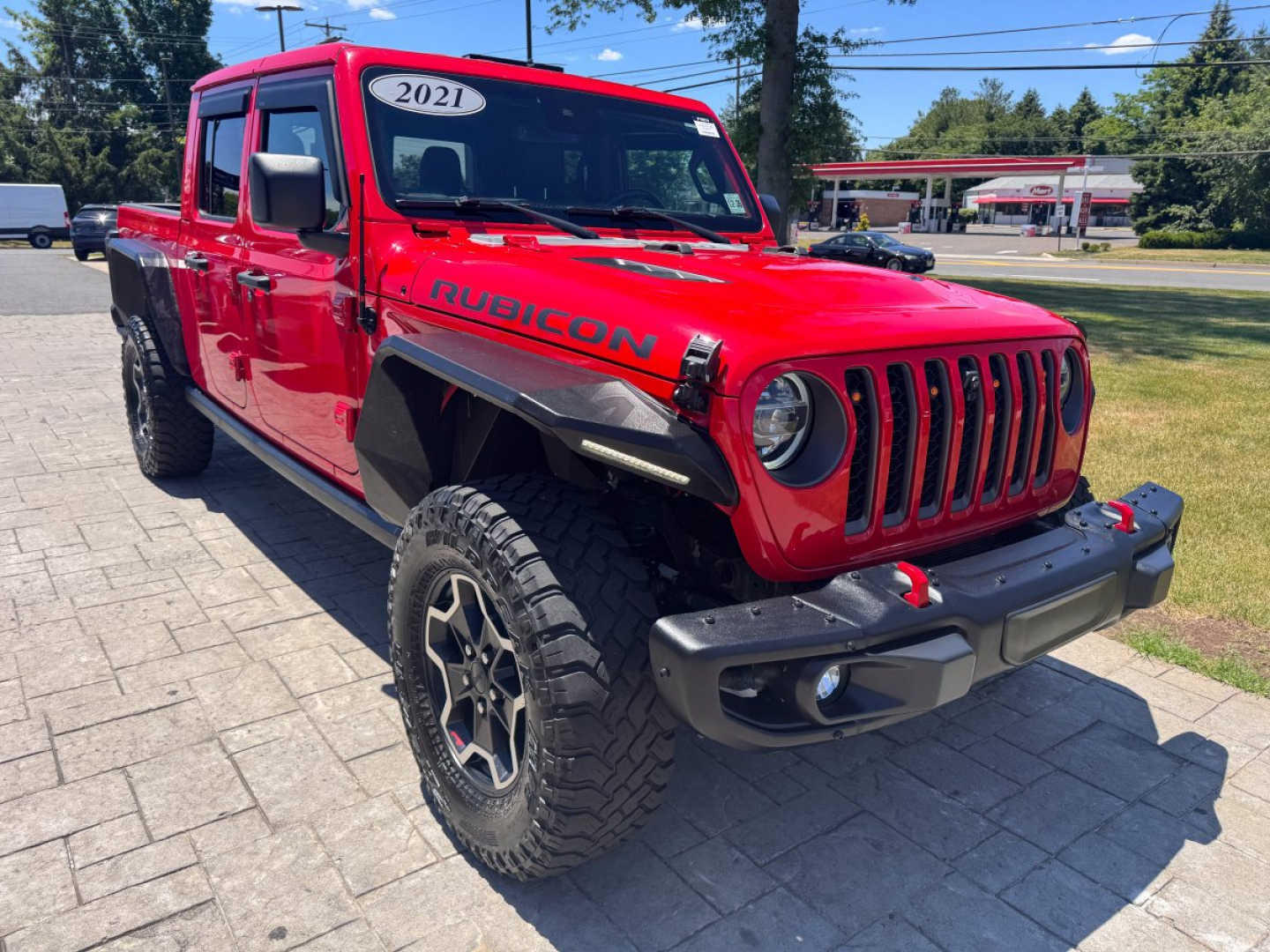 Jeep Gladiator Rubicon red pickup truck in front view showing front grille and wheels.