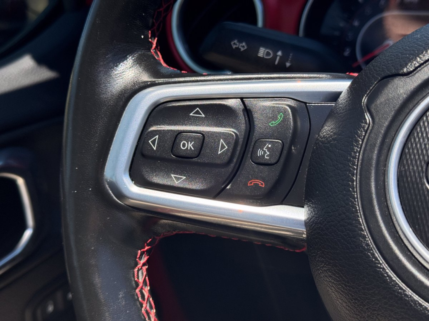 Jeep steering wheel controls with OK button and directional arrows, phone hang-up and answer buttons visible on left side of wheel.