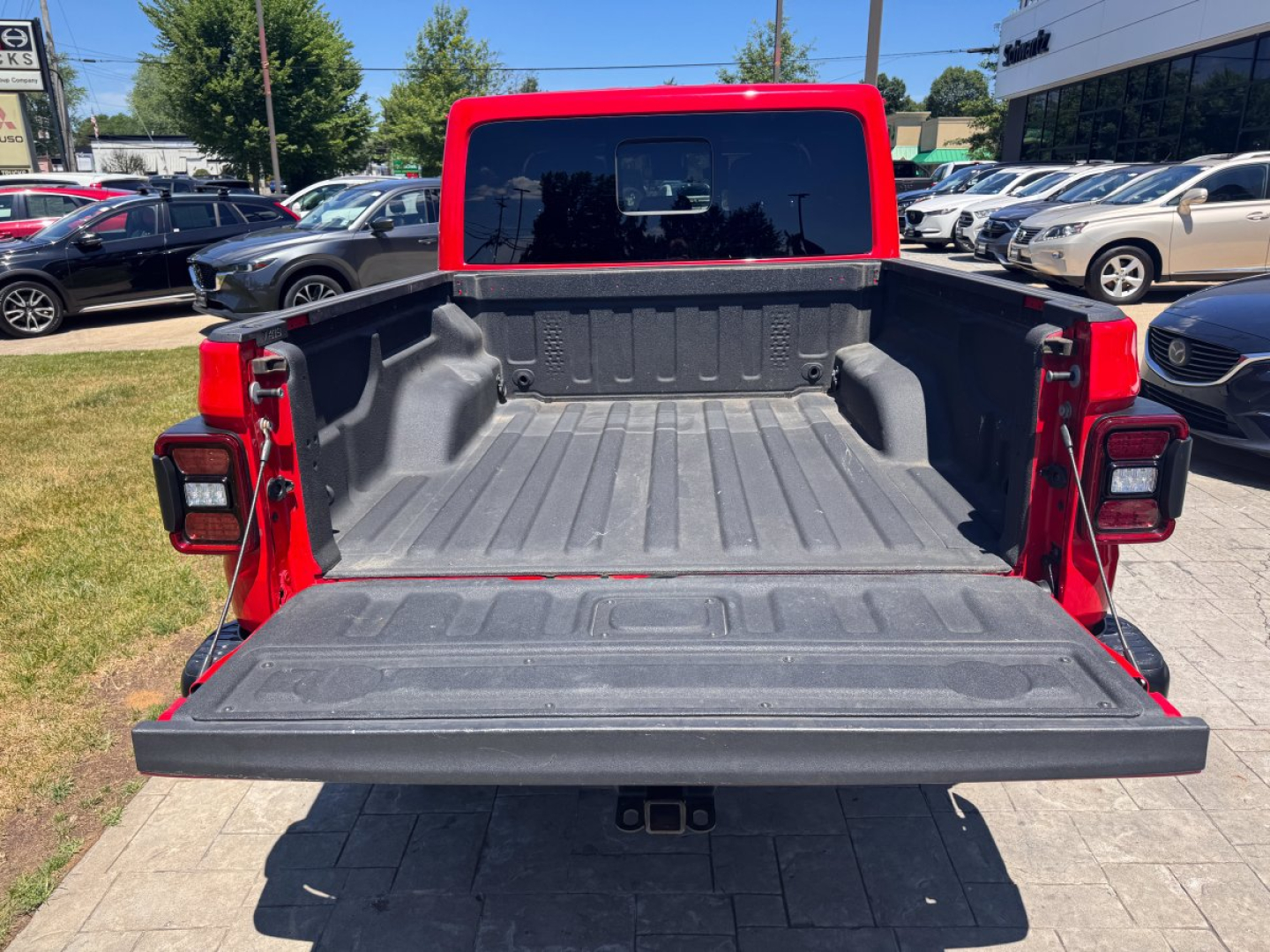 Rear view of a red 2021 Jeep Gladiator pickup truck with the tailgate down, showcasing the truck bed with textured bed liner and surrounding sidewalls.