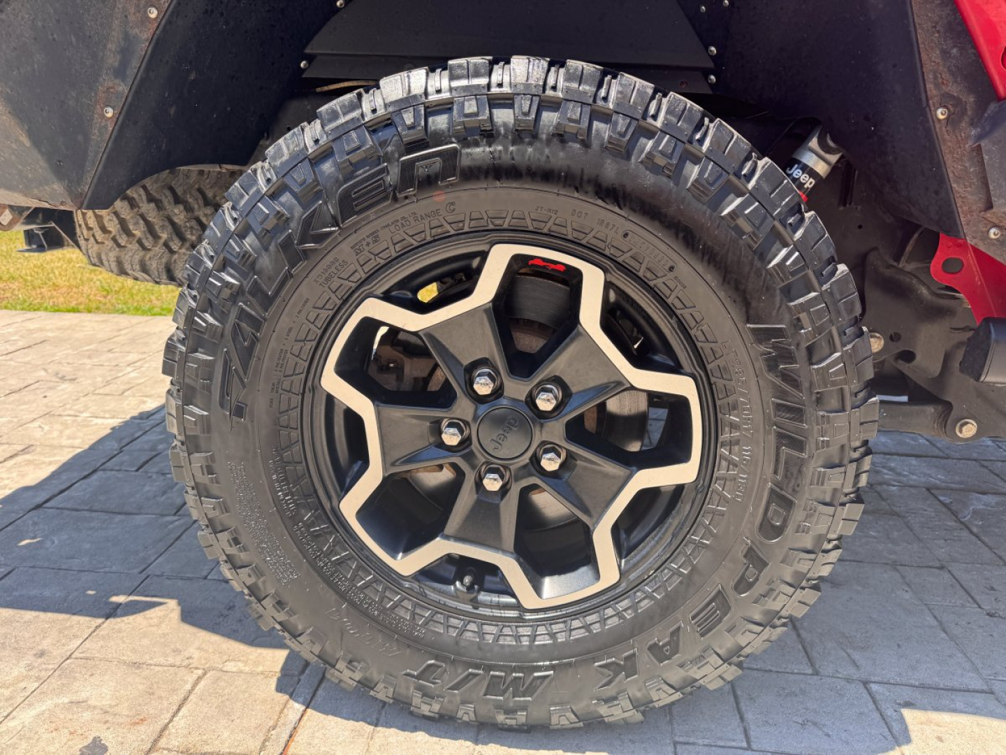 Wheel and tire close-up on a Jeep Gladiator with aggressive off-road tire tread and black alloy rim.