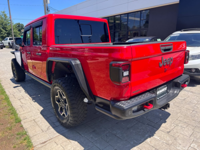 Red 2021 Jeep Gladiator pickup truck rear three-quarter view showing tailgate with Jeep badge and taillights, black bumper, and off-road tires.