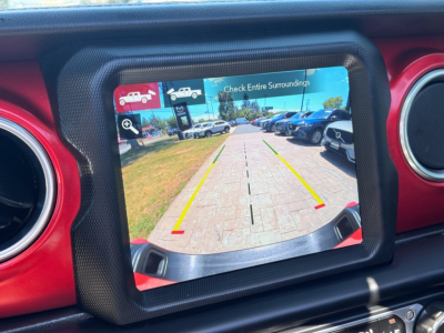 Jeep Gladiator rear view camera display showing backup guidelines and surrounding vehicles in a dealership lot.