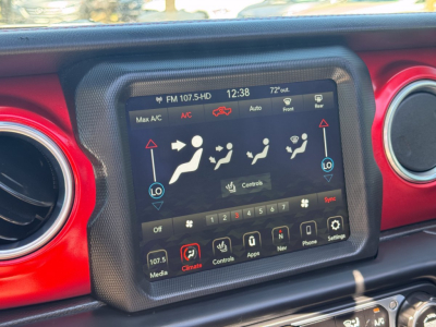 Center dashboard touchscreen in Jeep Gladiator showing climate controls and media icons in a red-accent cabin.