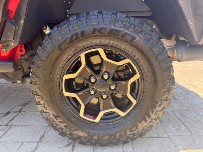 Close-up of front wheel and fender on a 2021 Jeep Gladiator showing rugged Falken tires and black alloy wheel with beige accents.
