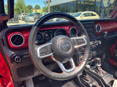 Jeep Gladiator interior steering wheel close-up showing dashboard controls, circular air vents, and gear shifter.
