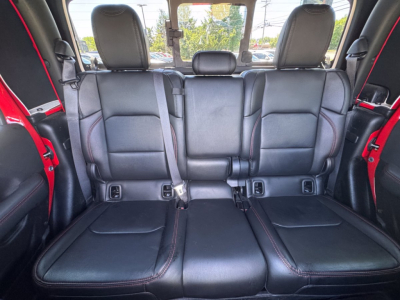 Jeep Gladiator rear 3-seat bench / back row shown in black leather upholstery with red stitching and seat belts visible