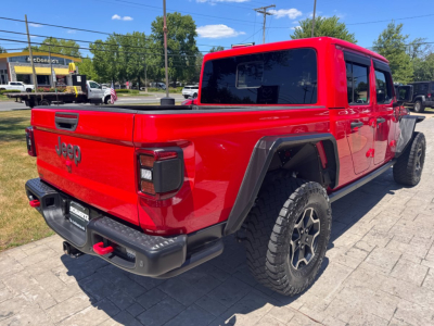 Red 2021 Jeep Gladiator pickup truck rear three-quarter view showing tailgate with Jeep logo, large off-road tires, and crew cab,”