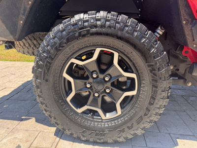 Wheel and tire close-up on a Jeep Gladiator with aggressive off-road tire tread and black alloy rim.