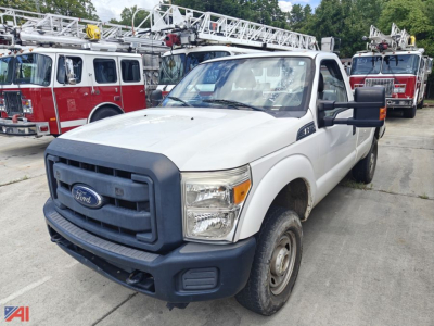 Ford F-250 pickup truck in a lot with fire trucks in background, white cab with black grille and bumper, steel wheels, N/A on this model.