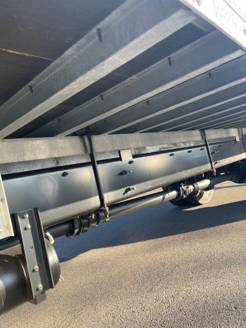 Underbody view of a box van truck showing suspension and frame rails with a cylindrical component and leaf spring hardware.