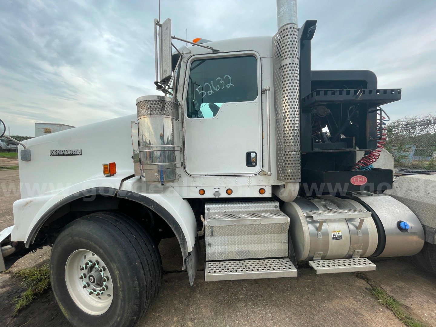 2014 Kenworth T800 side view showing cab, chrome exhaust stacks, aluminum fuel tanks, and steps. VIN tag not visible; truck in used condition with white/gray paint.