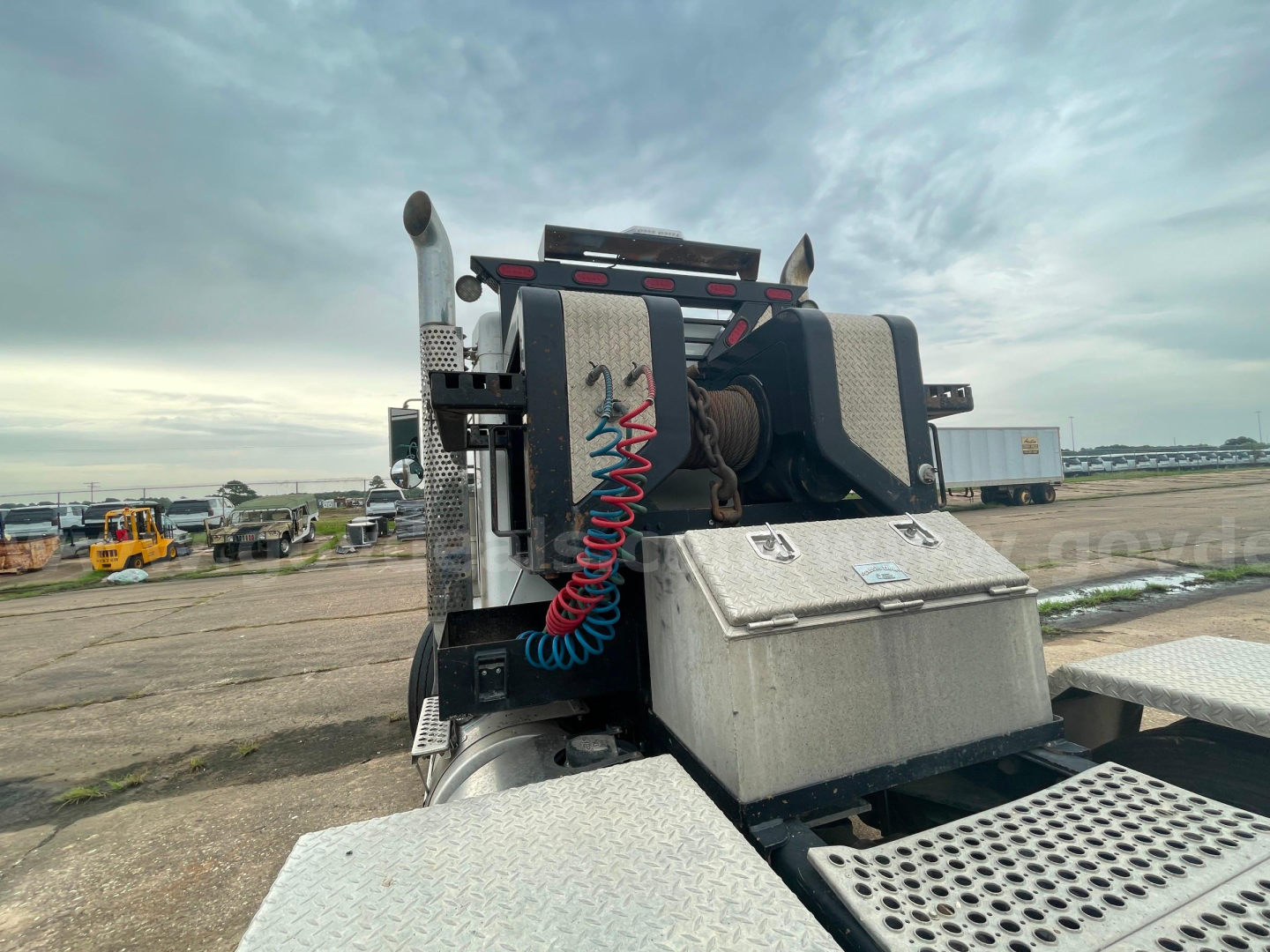 Kenworth T800 truck chassis with take-up winch and coiled red air line, metal platform, and toolbox visible from rear/side angle.