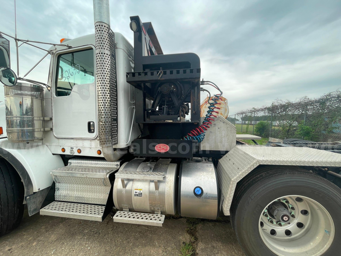 Kenworth T800 truck side view showing fuel tanks, chrome steps, and hydraulic line assembly with rear engine compartment.
