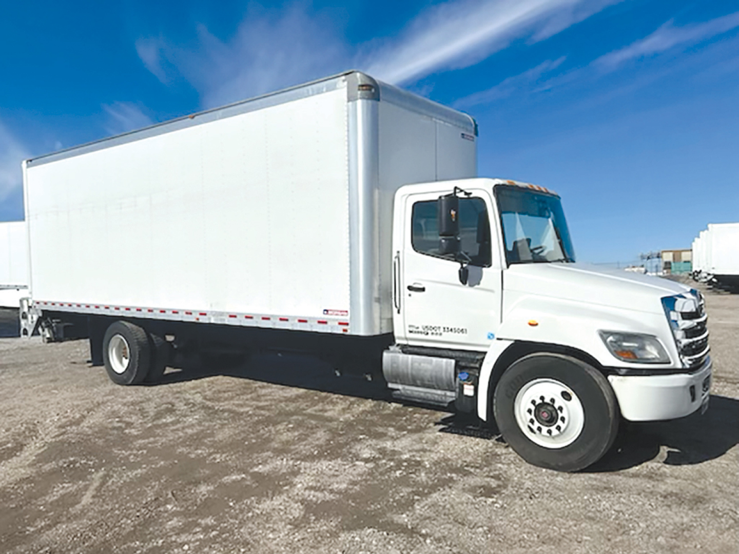 Truck cab in front-right view of a 2020 Hino 268A conventional daycab with white box body, cab doors, and dual rear wheels.