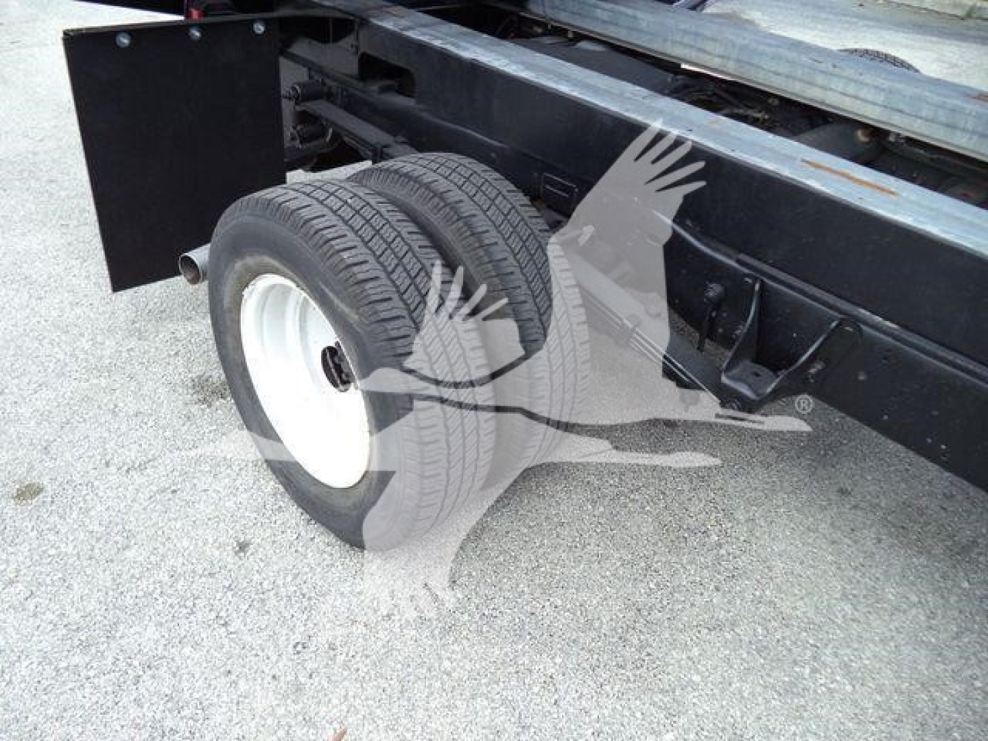 Ford E-450 dump truck rear wheel and chassis showing dual tires and suspension undercarriage.
