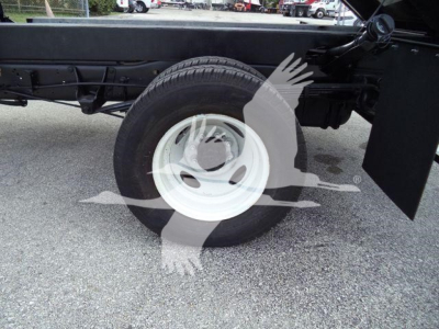 Ford E450 chassis showing single rear wheel and dump truck frame with attached white steel wheel.