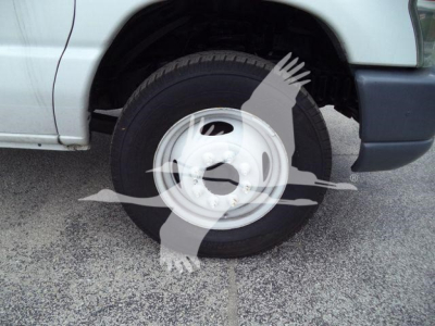Truck wheel and front fender of a 2011 Ford E450 dump truck showing the front wheel and tire.