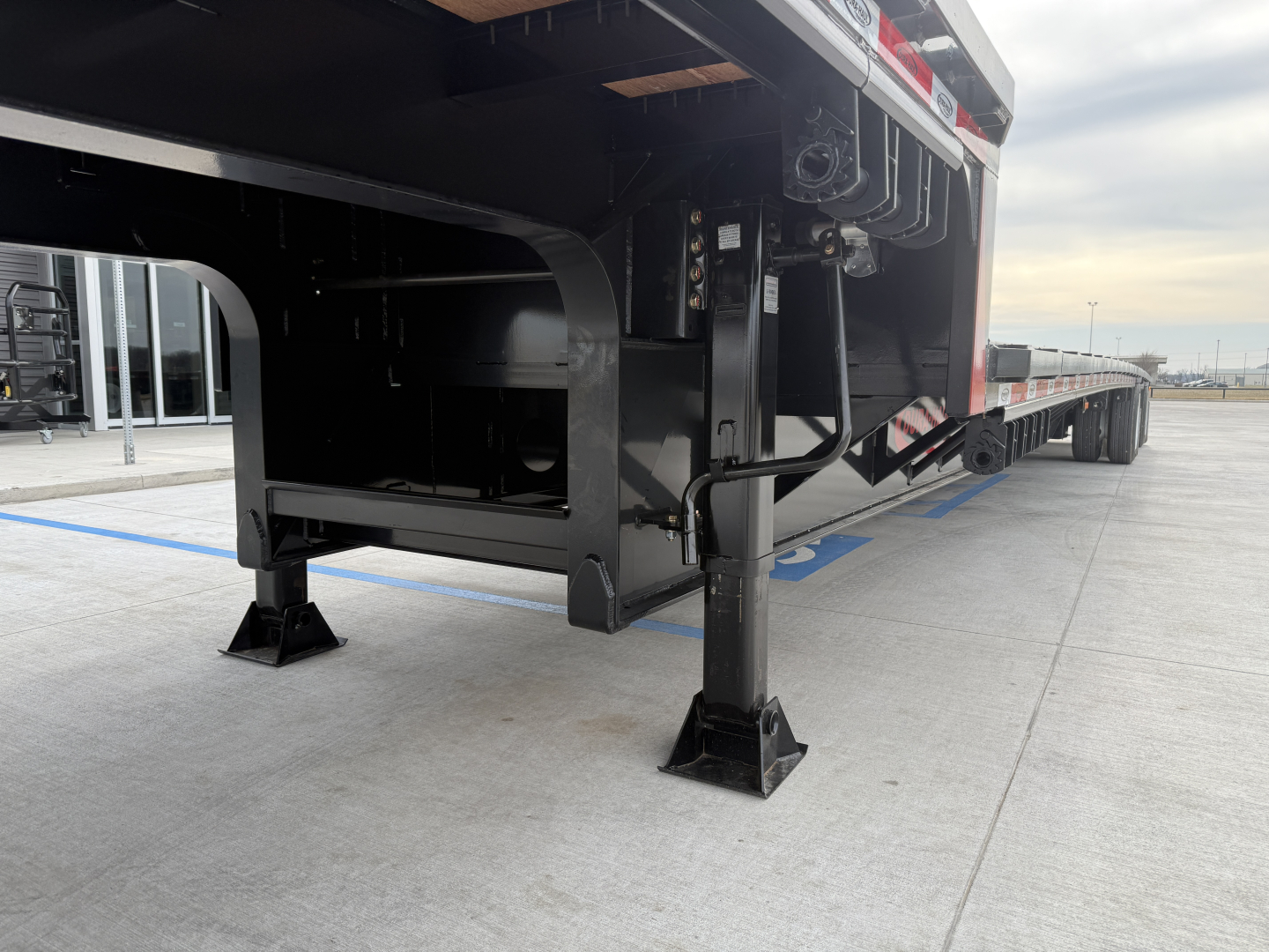 Trailer undercarriage view of a new 2026 Dura Haul drop deck 53' spread trailer showing landing gear, front legs, and underbody frame with black paint.