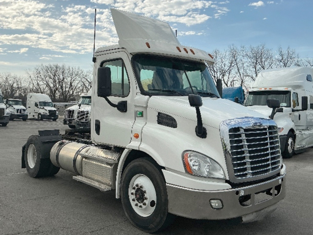Truck cab in service view showing Freightliner Cascadia113 daycab with chrome grille and dual fuel tanks.