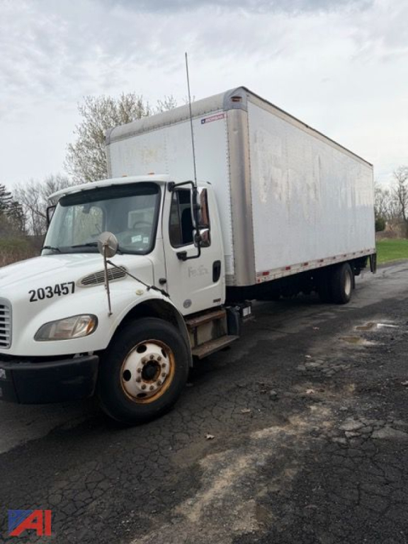 Box truck front-left view showing Freightliner M2 106 with box cargo area and wheel in foreground.