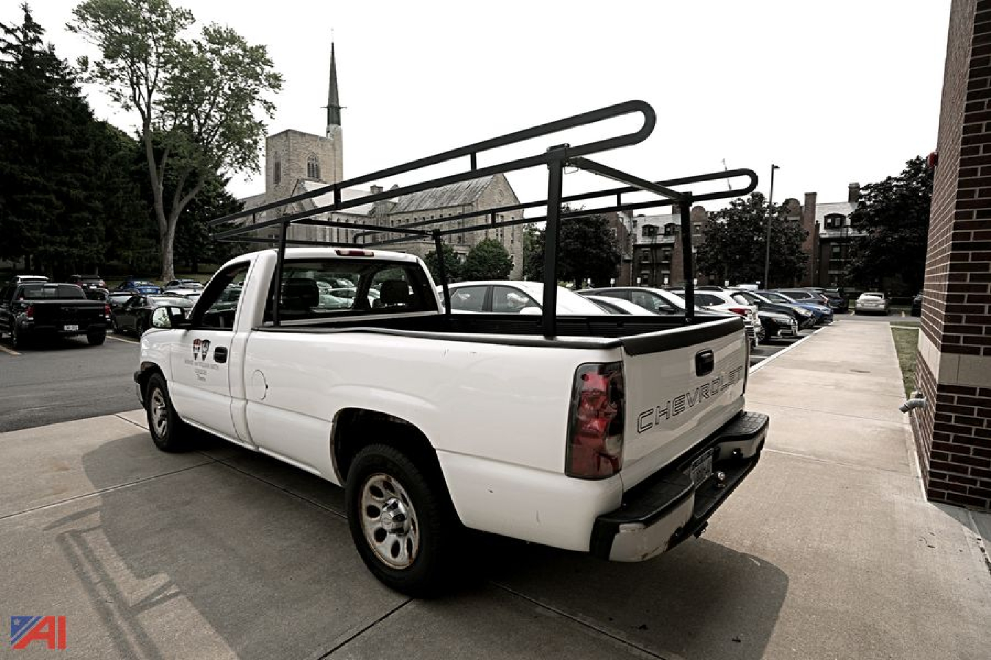 Chevrolet Silverado 1500 pickup truck in a parking lot, white two-door extended cab, rear cargo rack with ladder bars mounted, tailgate visible.