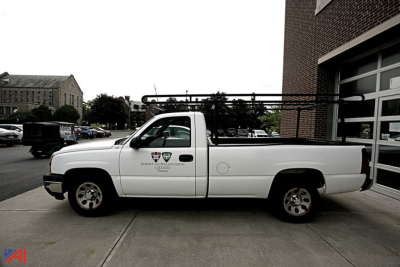 Chevrolet Silverado 1500 pickup truck side view showing ladder rack and crew cab, white color, with badges on front door.