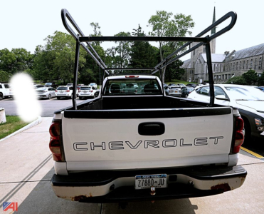 Chevrolet Silverado 1500 pickup truck tailgate view with a metal rack over the bed, rear bumper, and license plate visible