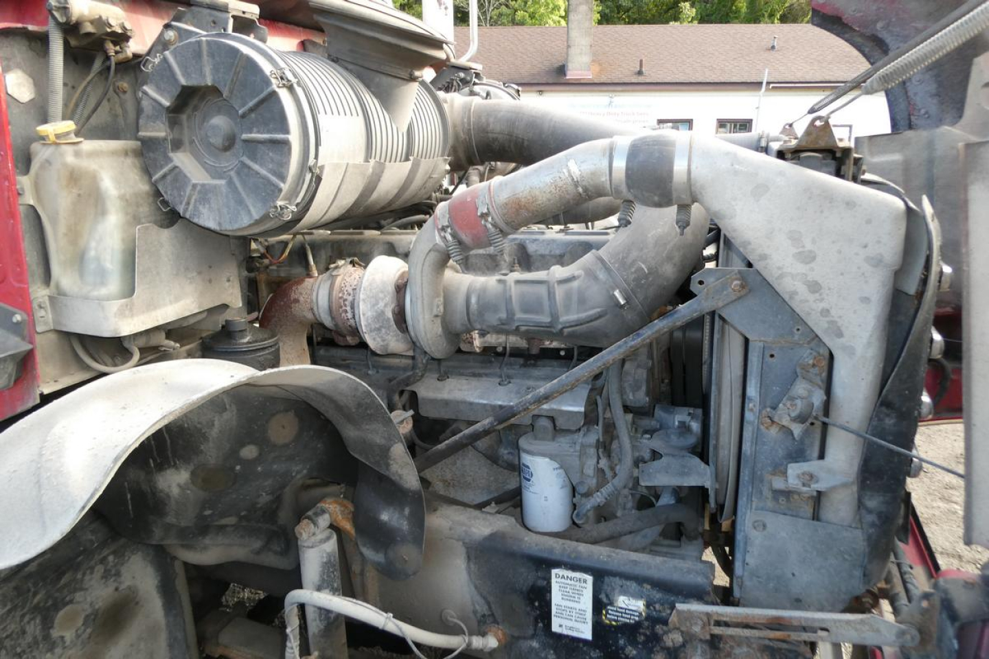 Mack CV (Granite) CV713 engine bay showing air filter housing, hoses, and radiator area in serviceable truck.