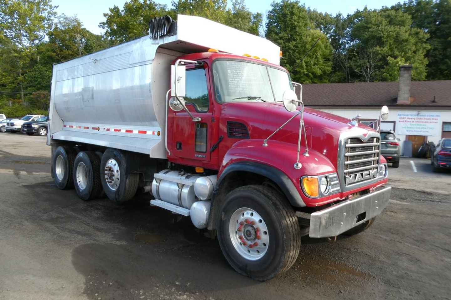Mack CV Granite dump truck 2005 CV713 with red cab and silver dump body, front grille, headlights, and dual rear wheels.