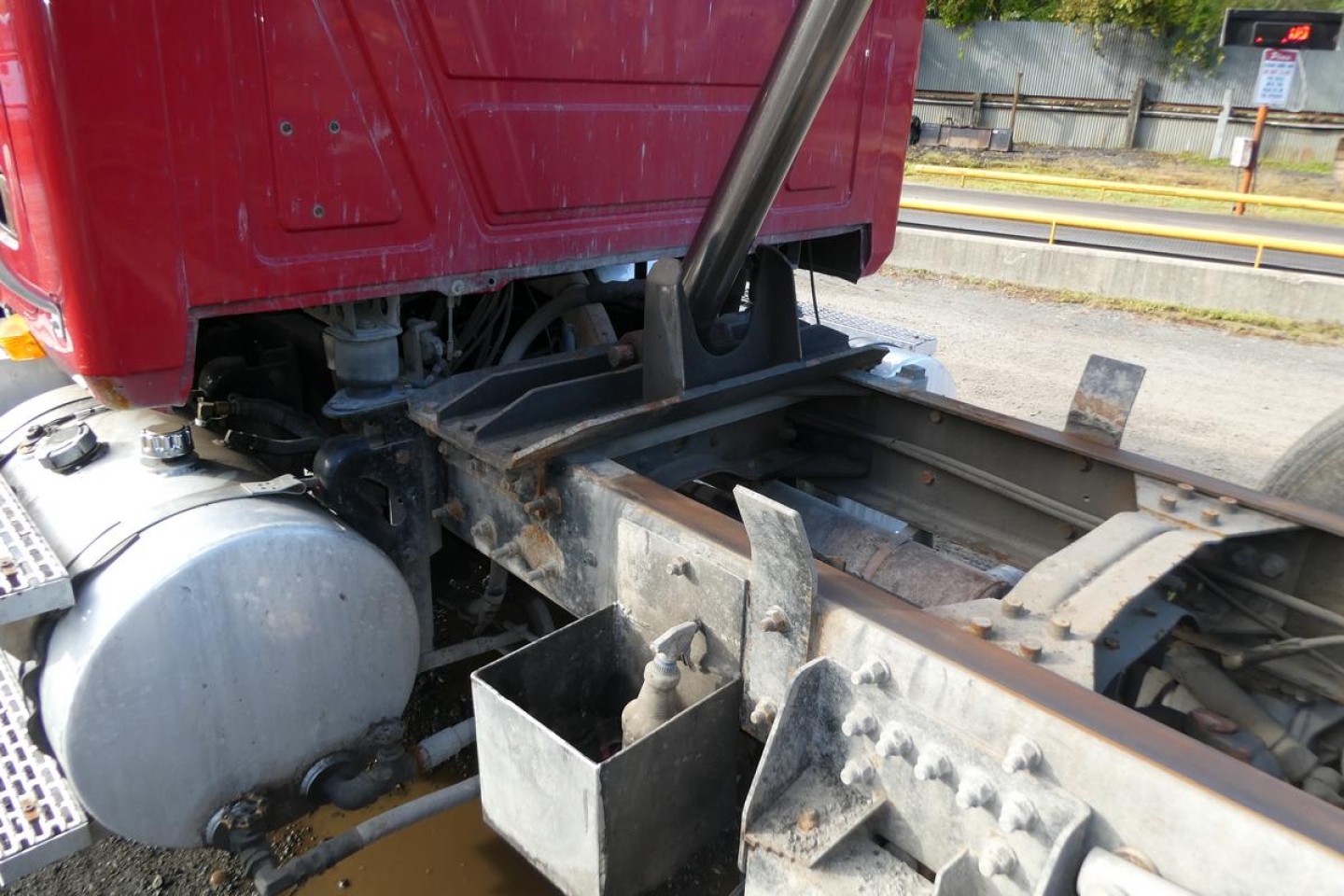 Truck chassis and fifth wheel area of a 2005 Mack CV (Granite) CV713 dump truck showing frame rails, hydraulic system, and wheel area.