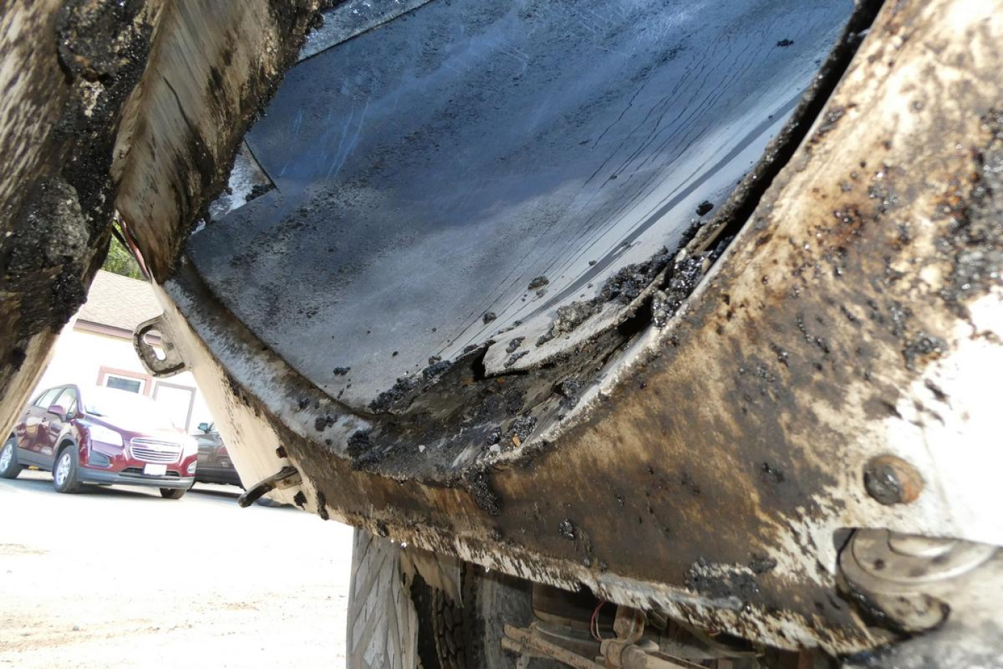 Truck dump bed underside with mud and wear visible showing damaged seal and dirt.