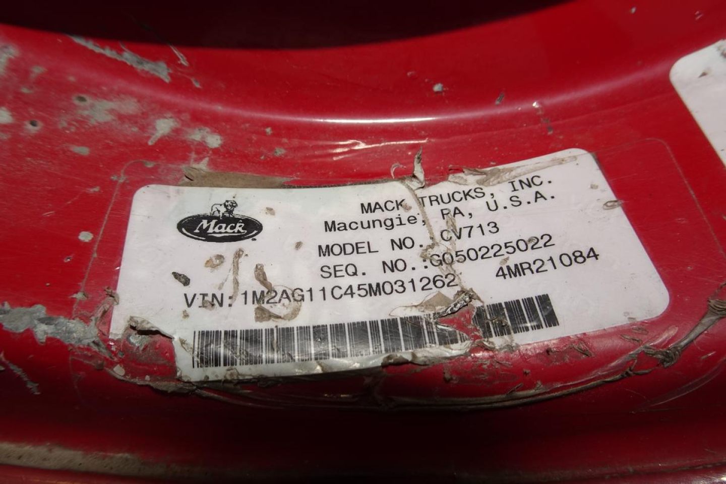 Mack CV/Granite chassis label showing model CV713, VIN 1M2AG11C45M031262, SEQ NO GO5025022, serial 4MB21084, Mack Trucks Inc sticker on red frame.