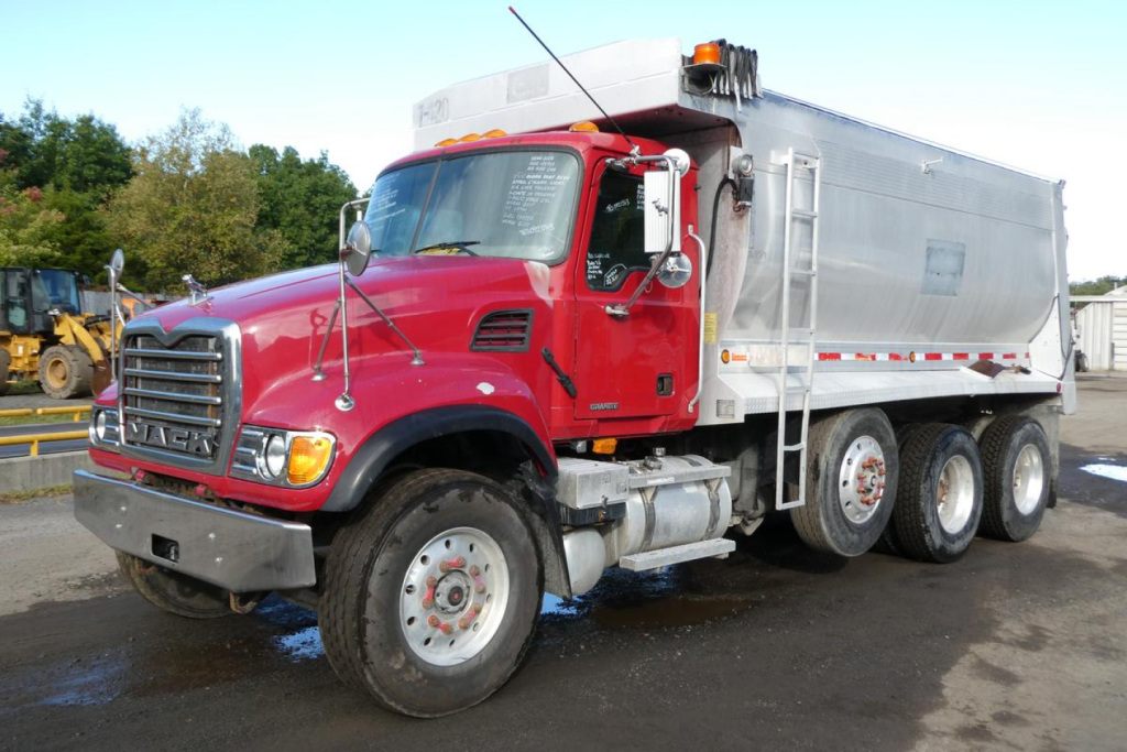 Mack CV series dump truck showing granite-style aluminum dump body and red cab with large chrome front grille.