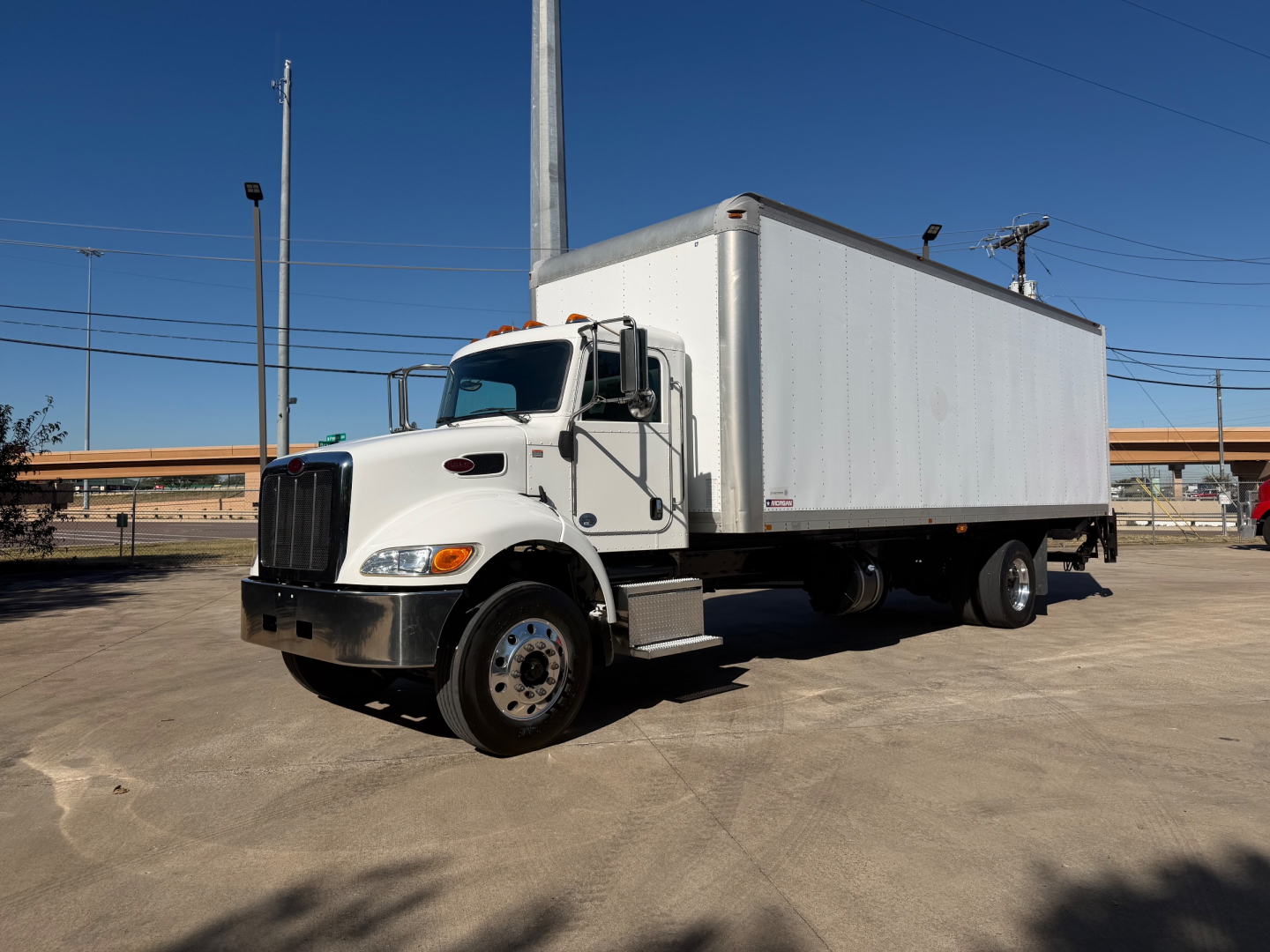 Peterbilt 337 box truck in a parking lot with white cab and large box cargo area, side view showing front of truck.